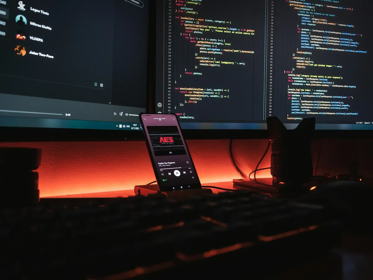 Çoklu monitörde kod ve ön planda uygulama gösteren telefon